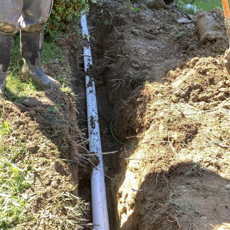 Sewer line replacement trench with exposed pipe and boots Sewer line replacement trench with exposed pipe and boots