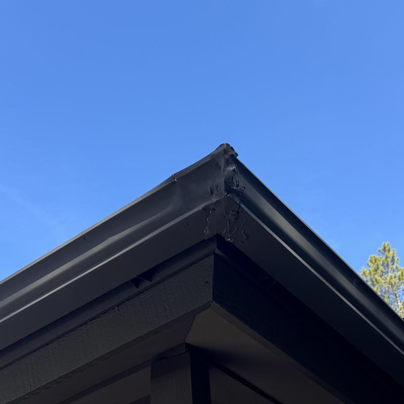 Gutter system corner with sealant repair, clear sky