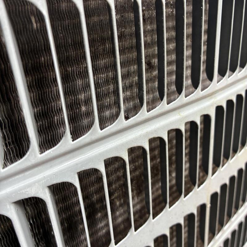 Heat pump condenser coil close-up showing metal fins Heat pump condenser coil close-up showing metal fins