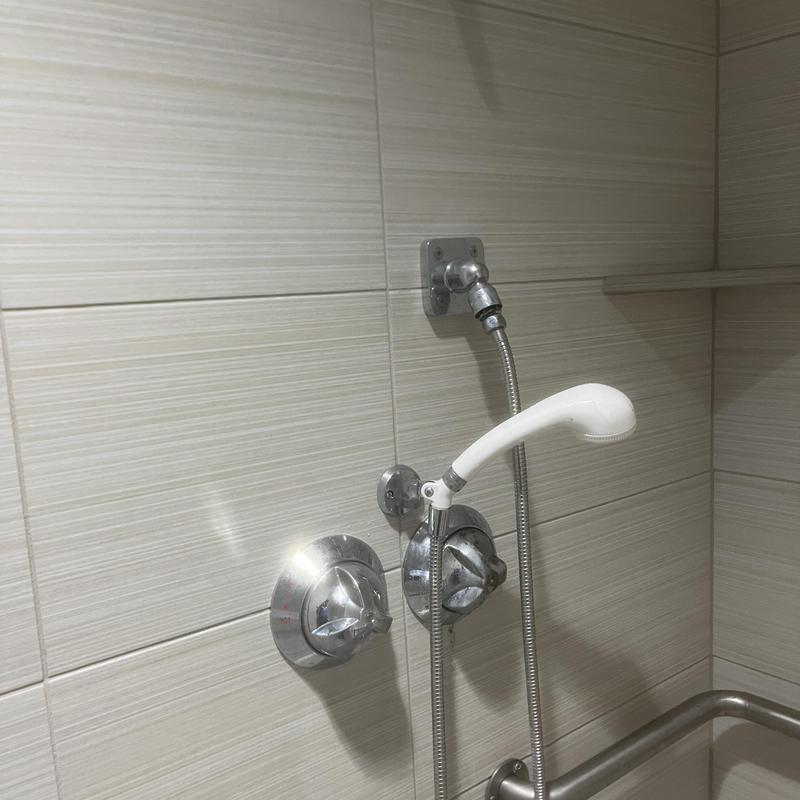 Shower valve and handheld showerhead in tiled locker room Shower valve and handheld showerhead in tiled locker room