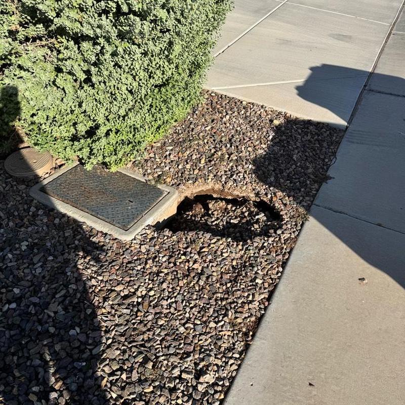 Water meter area sinkhole with gravel and sidewalk