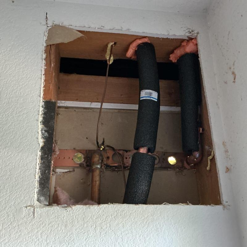 Copper water lines with foam pipe insulation inside wall cavity