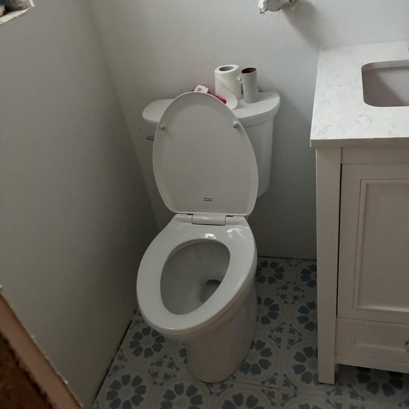 Toilet with open lid in bathroom near sink cabinet
