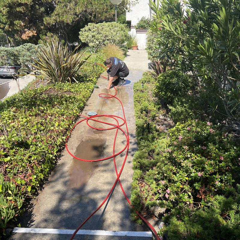 Storm drain hydro jetting with red hose and technician Storm drain hydro jetting with red hose and technician