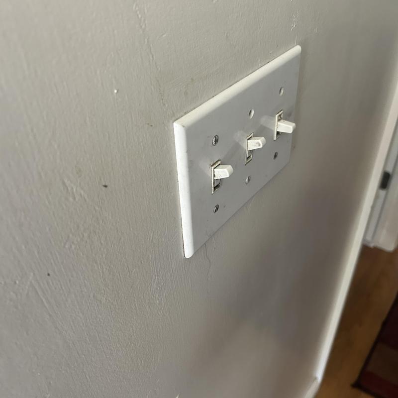 Three-way light switch panel on drywall wall in home