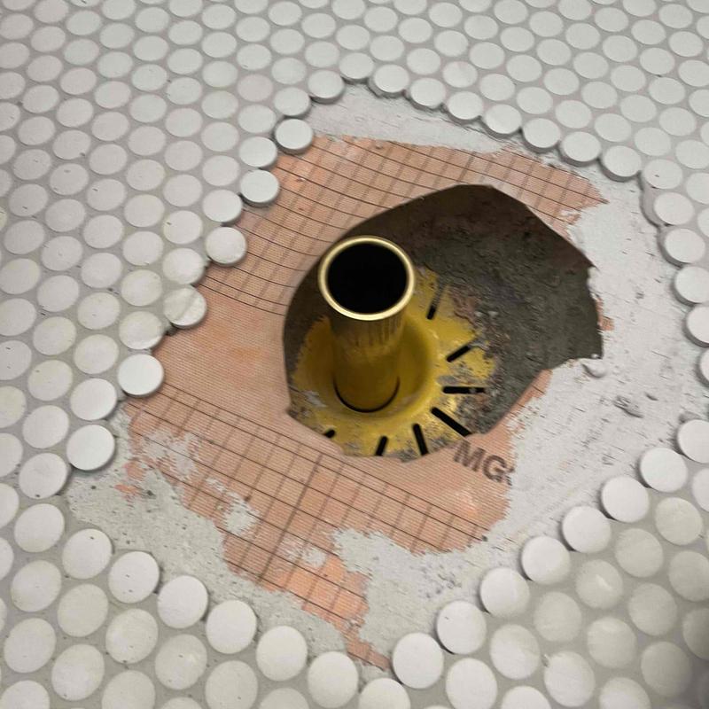 Shower drain and tile floor with exposed plumbing