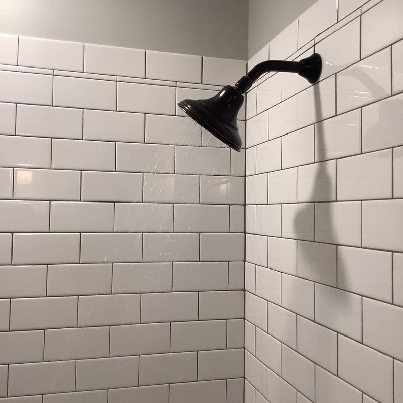 Shower faucet with water flow and white tile wall Shower faucet with water flow and white tile wall