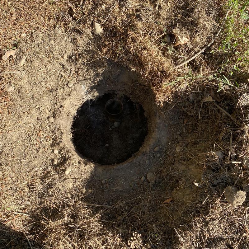 Septic tank opening with exposed pipe in soil
