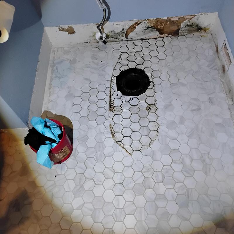 Toilet flange on tiled bathroom floor with water damage
