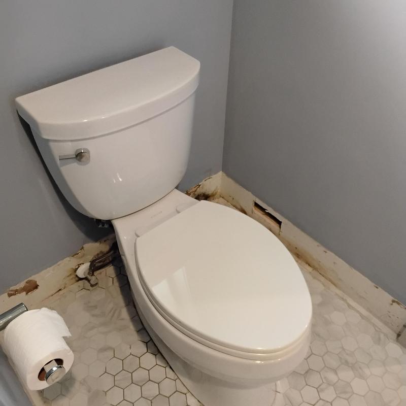 Toilet with sealed base in bathroom corner