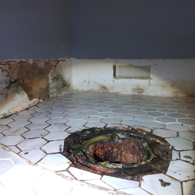 Toilet flange and damaged floor tile in bathroom