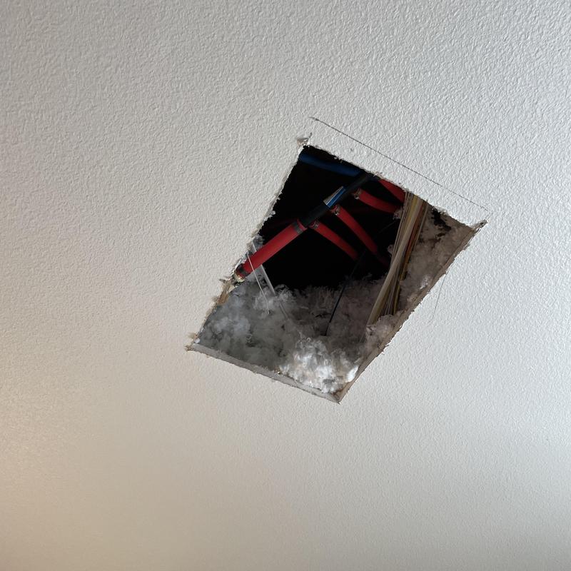 PEX plumbing manifold in ceiling with insulation exposed