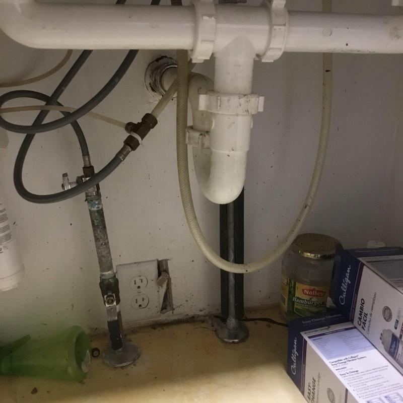 Kitchen sink drain pipes and water supply lines under cabinet