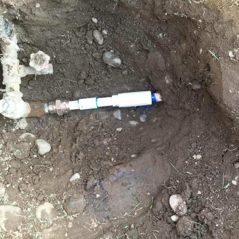 Main water line with new pipe fitting in trench