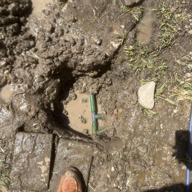 Irrigation pipe leak with clamp repair in muddy ground