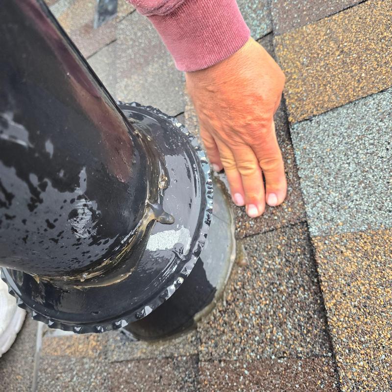Pipe jack on shingle roof with hand inspecting leak Pipe jack on shingle roof with hand inspecting leak