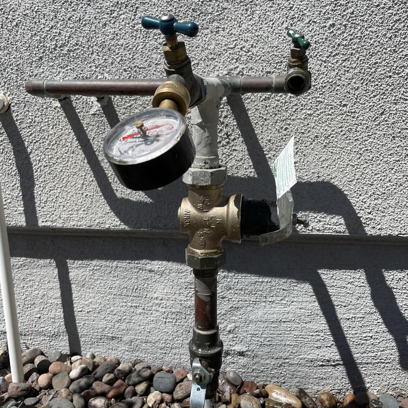 Pressure regulator valve and gauge on outdoor plumbing