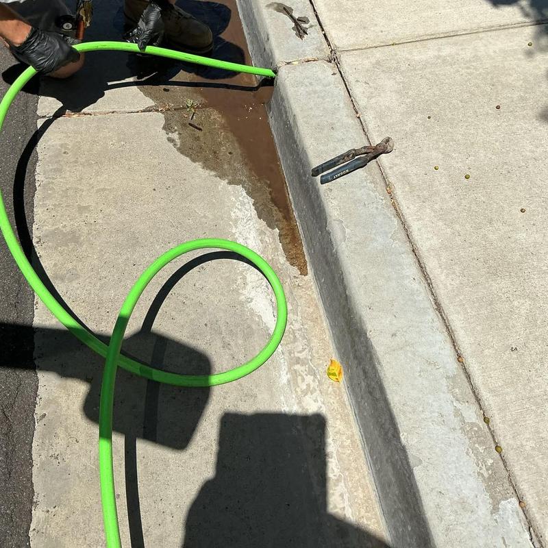Area drain hydro jetting with green hose on curbside