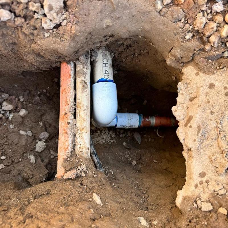 PVC irrigation line with copper fitting repair in dirt hole