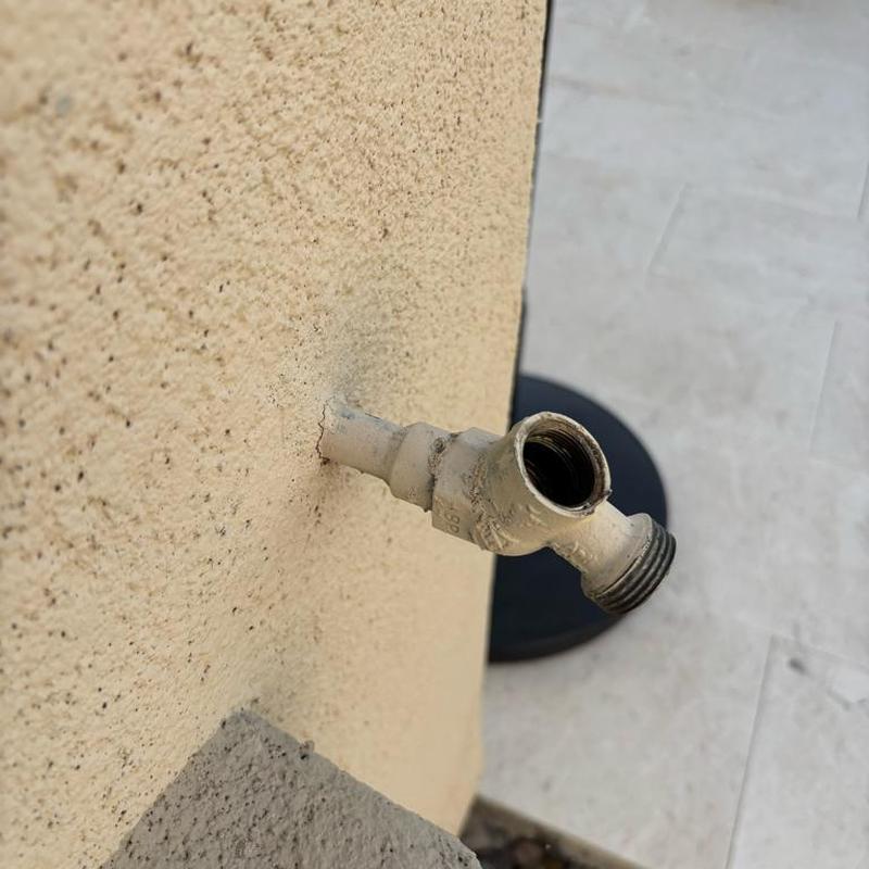 Outdoor hose bib pipe protruding from stucco wall