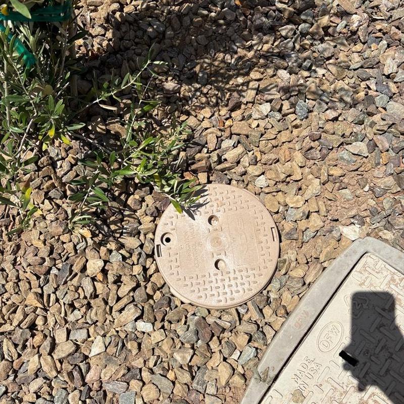 Pressure relief valve with tan access box in gravel yard