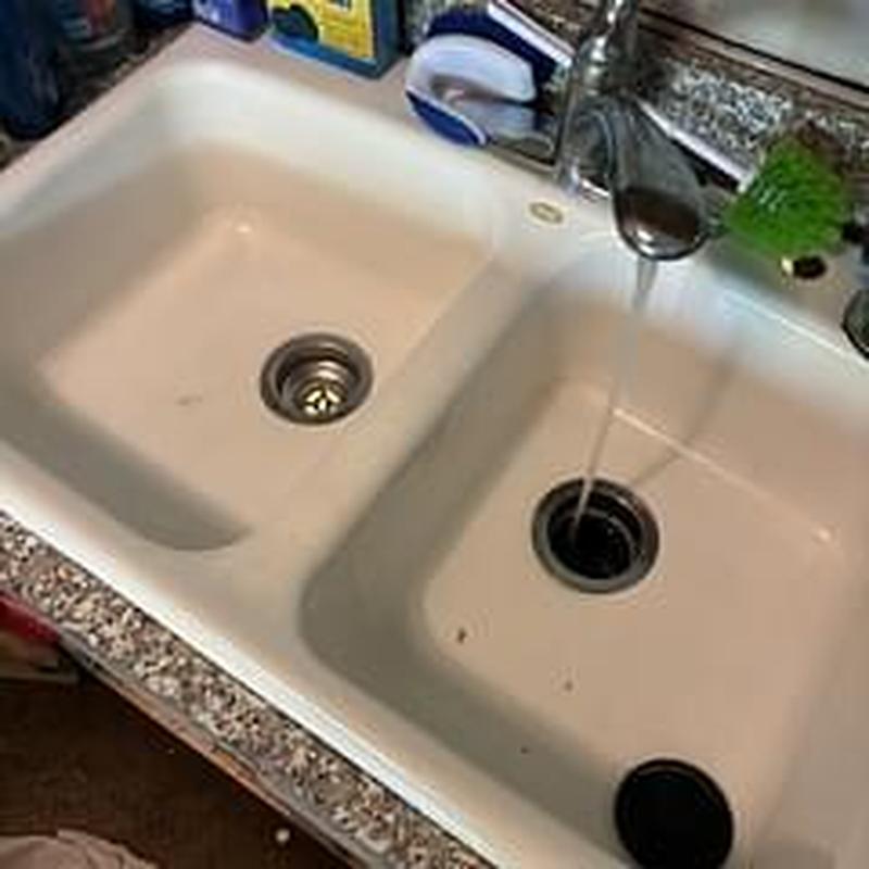 Kitchen sink drain with running water and cleaning supplies