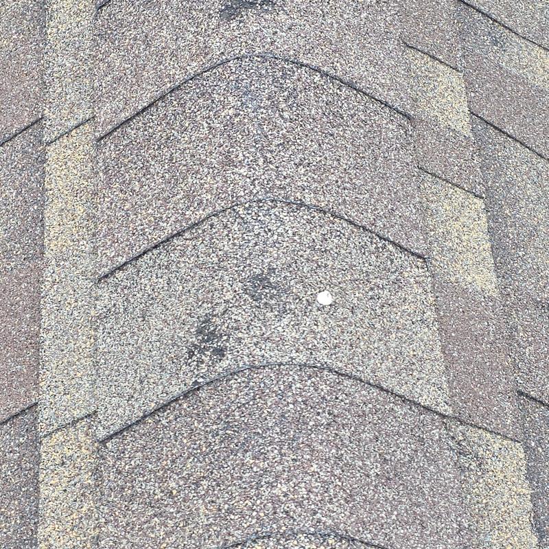 Asphalt roof shingles with hail damage impact mark