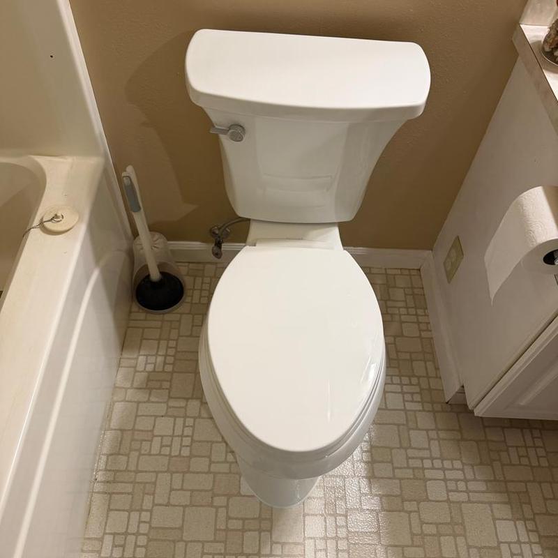 Toilet replacement in small bathroom with plunger nearby
