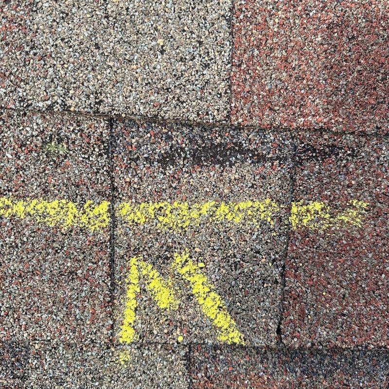 Asphalt shingles with hail damage marked in yellow