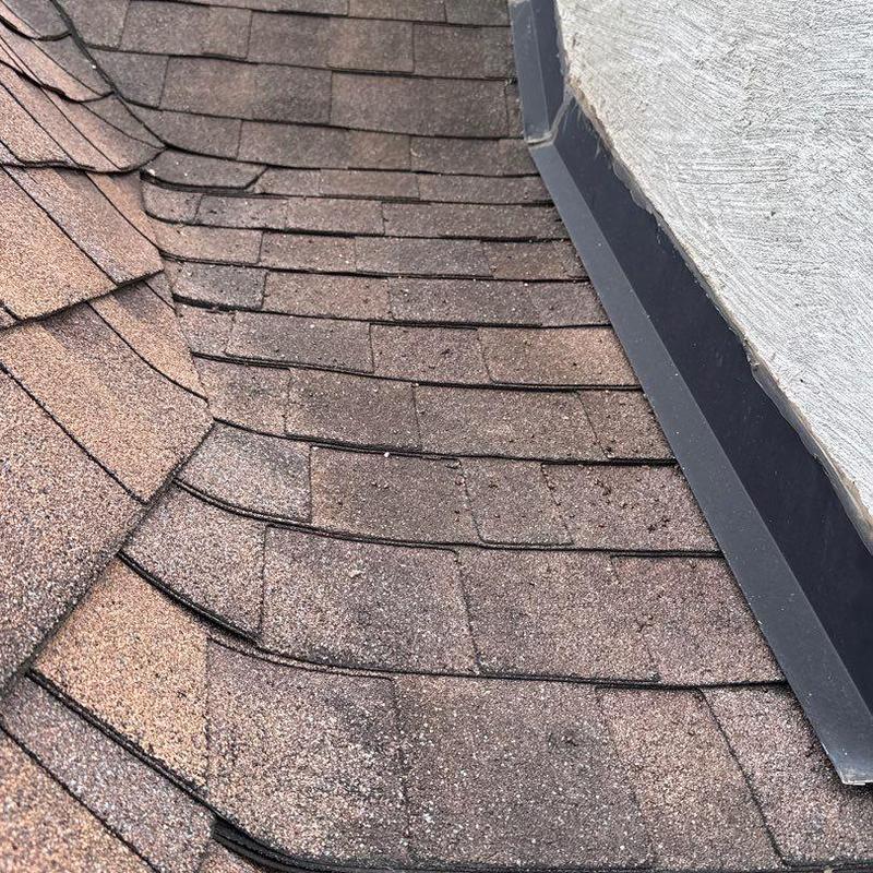 Roof shingles with hail damage near flashing system