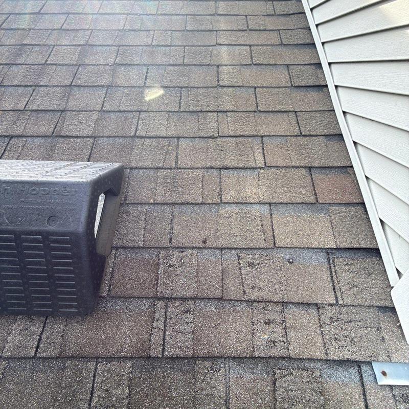 Asphalt shingle roof with hail damage near vent system