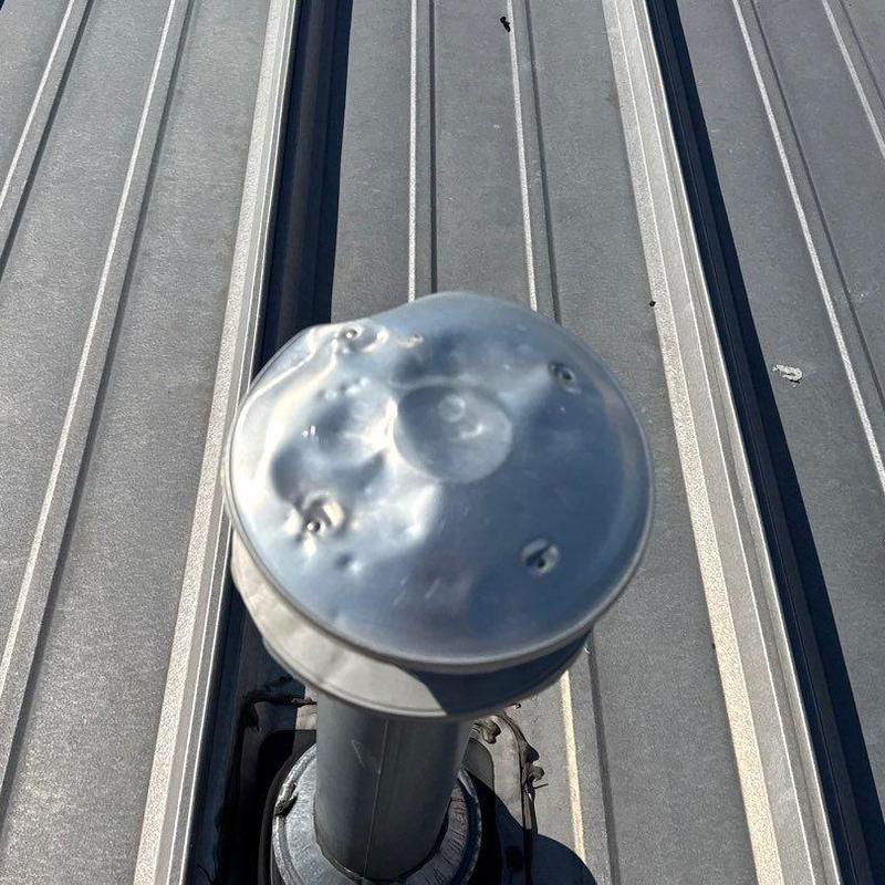 Metal roof vent with hail damage on commercial roof