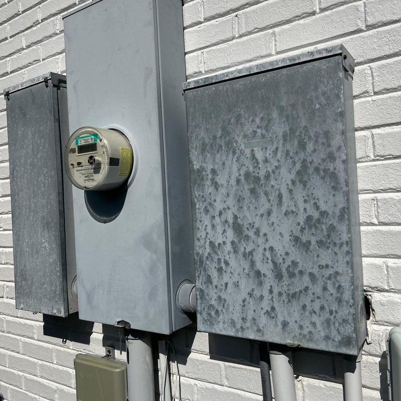 Electric meter and service panels on brick wall