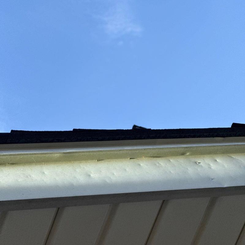 Gutter fascia with hail damage dents under roof edge