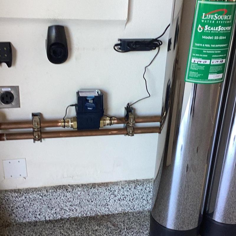 Water meter installed on copper piping with water system tanks
