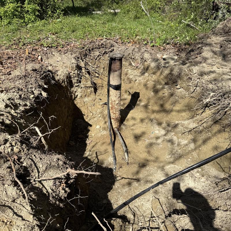 Well pump and piping exposed in dug soil pit Well pump and piping exposed in dug soil pit