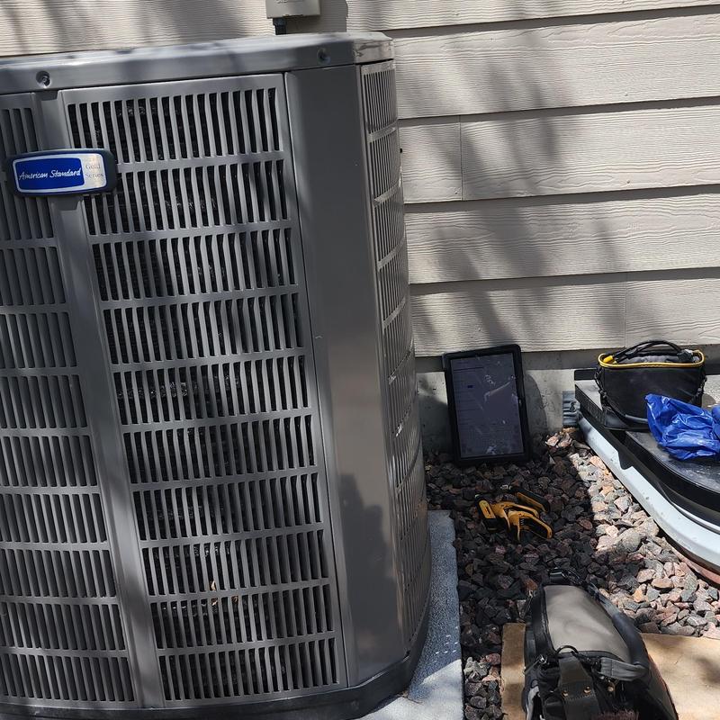 American Standard air conditioner with technician tools outside