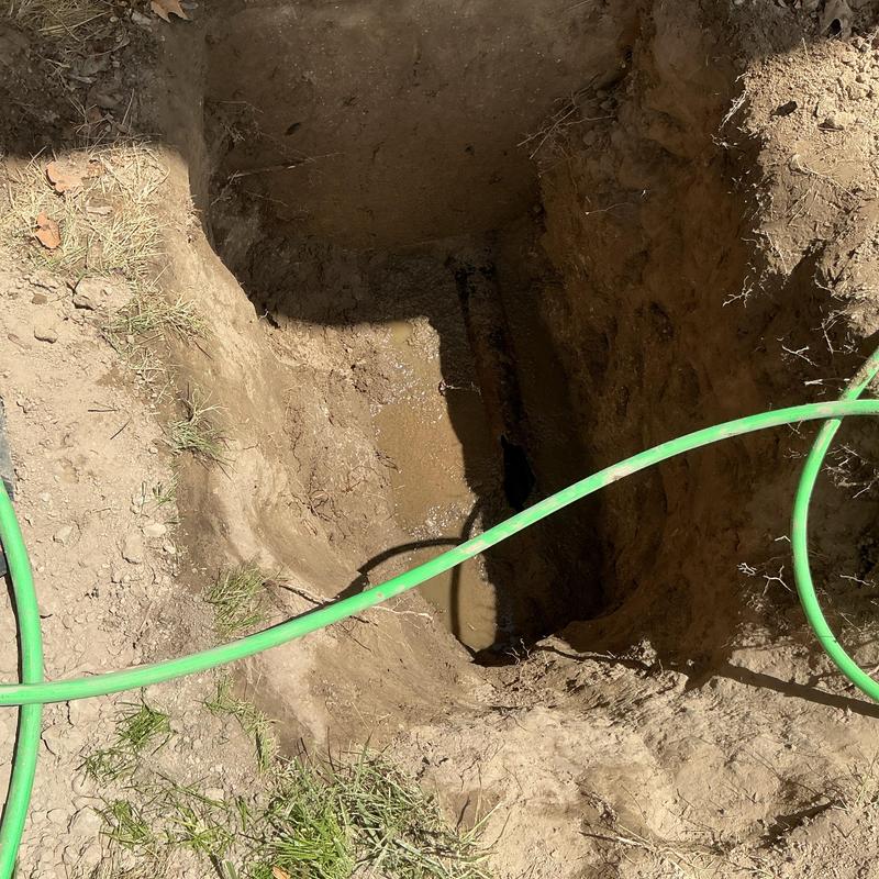 Outside sewer line cleanout excavation with green cable hose Outside sewer line cleanout excavation with green cable hose