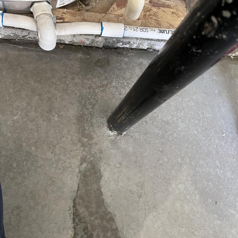 Basement floor leak near black support post and pipes