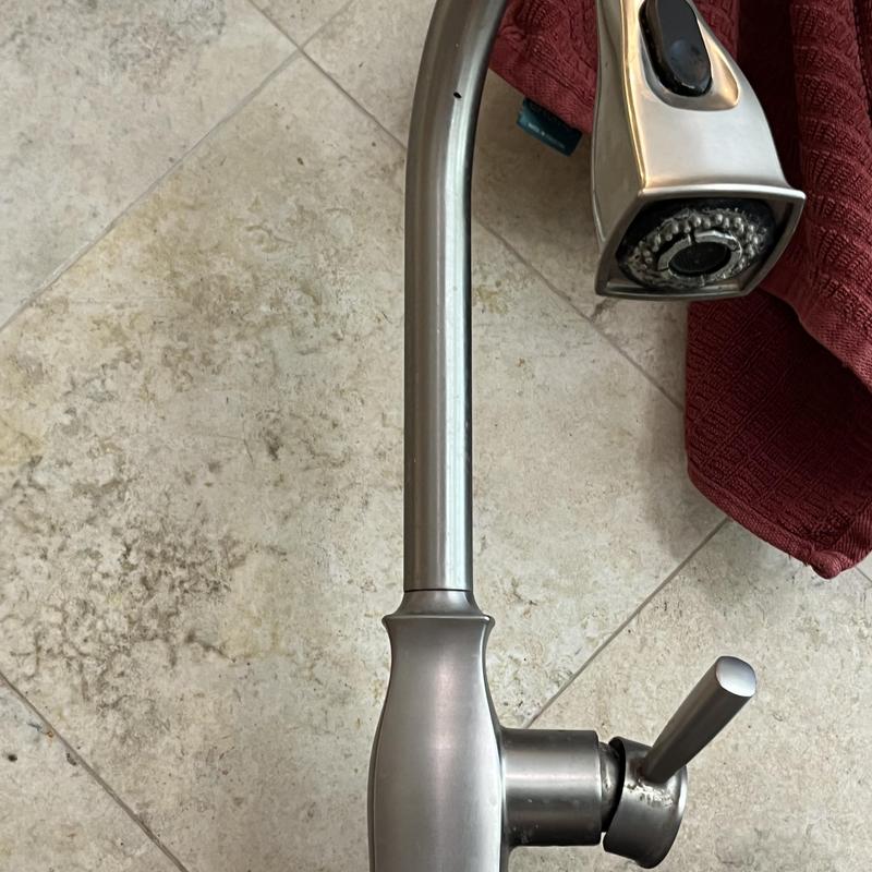 Delta kitchen faucet and spray head on tile floor