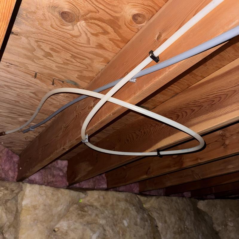 PEX tubing secured to wooden joists in crawl space PEX tubing secured to wooden joists in crawl space