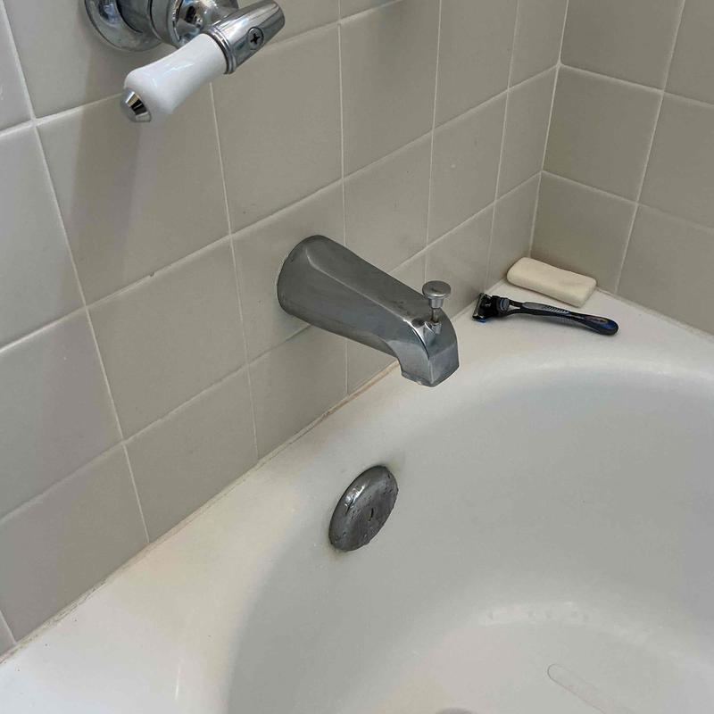 Tub spout and bathtub drain in tiled bathroom