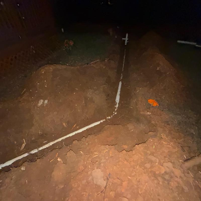 Sewer service line underground installation at night Sewer service line underground installation at night