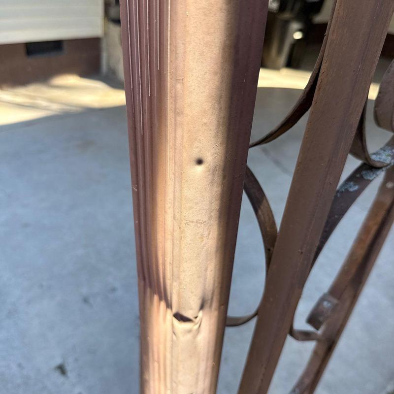 Metal downspout with hail damage dent and discoloration