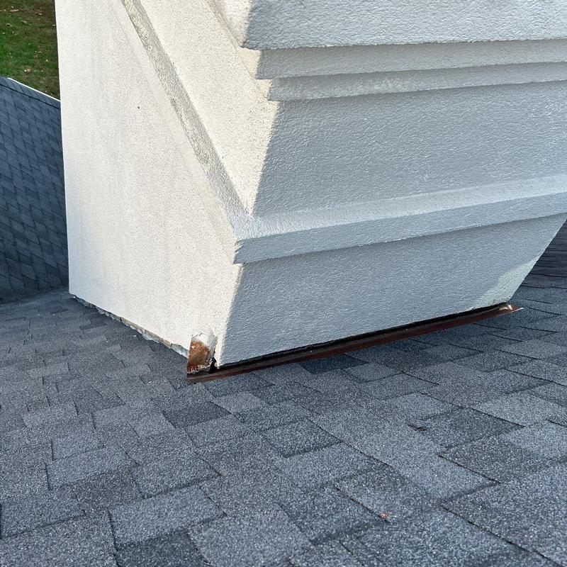 Roof flashing at chimney base with rust damage