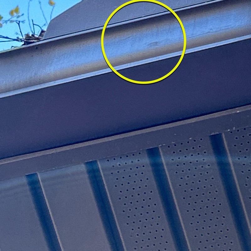 Metal gutter with visible hail dents under roof edge