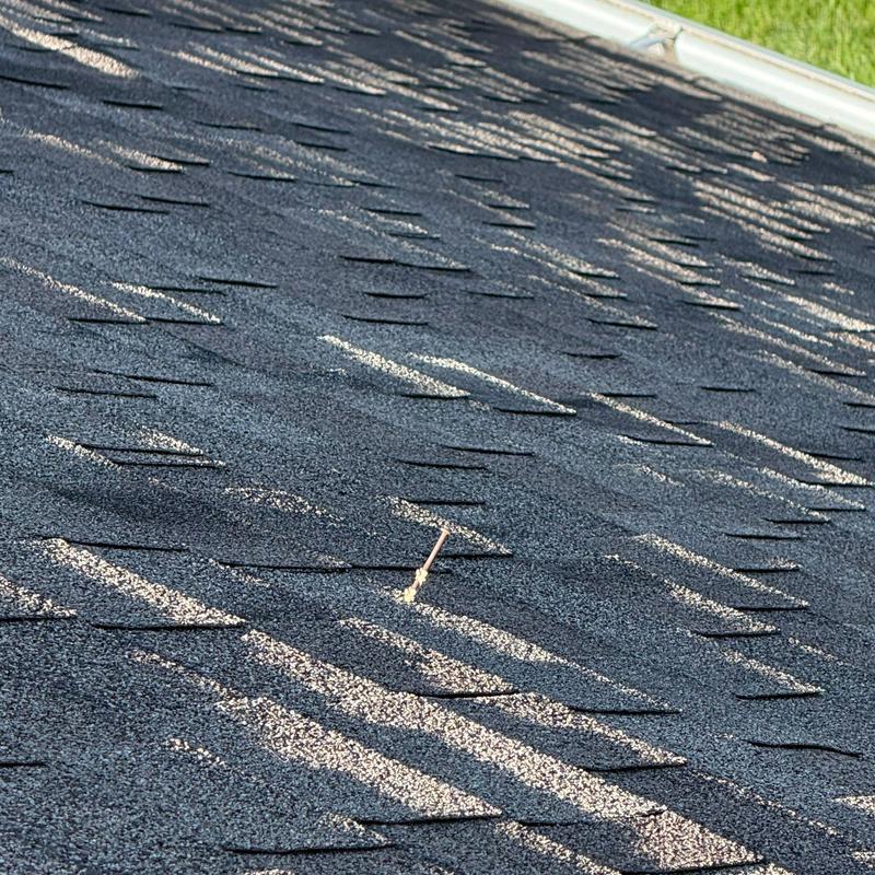 Asphalt shingles with nail damage on roof surface