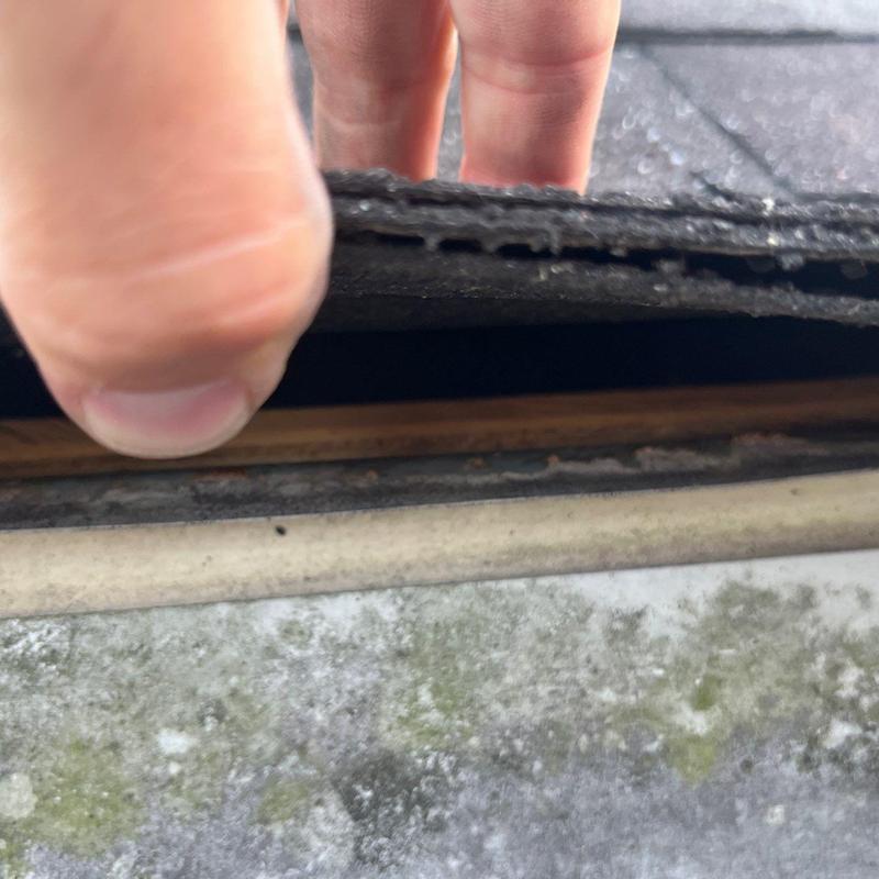 Roof shingles lifted to inspect hail damage and flashing