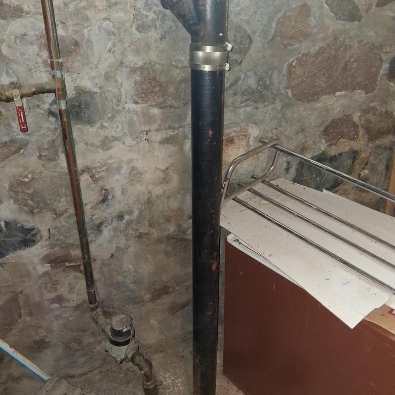 Cast iron drain pipe with metal hanger in basement