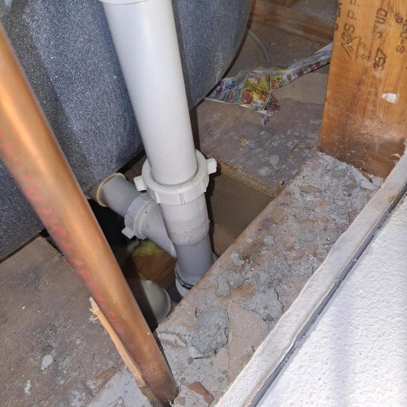 Trip waste drain pipes under bathtub in floor cavity